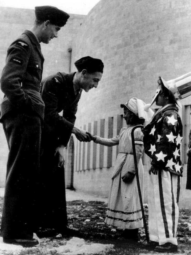 שני חיילים מחיל התעופה המלכותי מברכים ילדים המחופשים לדגל האמריקאי ולאחות, ירושלים 1942 (PHG\1005472)