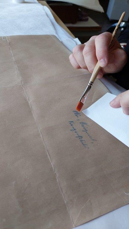 הכנות לשטיפה: המשמרת מוודאת שהדיו לא מתמוסס בגב הציור.