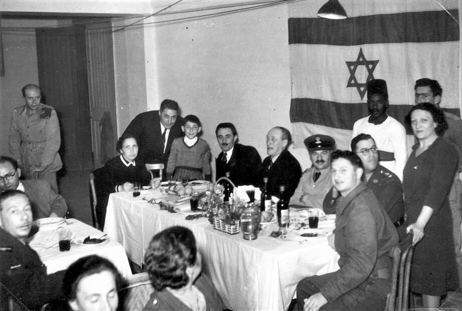 הדגל הציוני מאחורי משה שרת ומשפחתו בחברת קצינים בריטיים בחגיגות ליל הסדר בקהיר, מצרים, 19.4.1943 (PHAL\1611079)