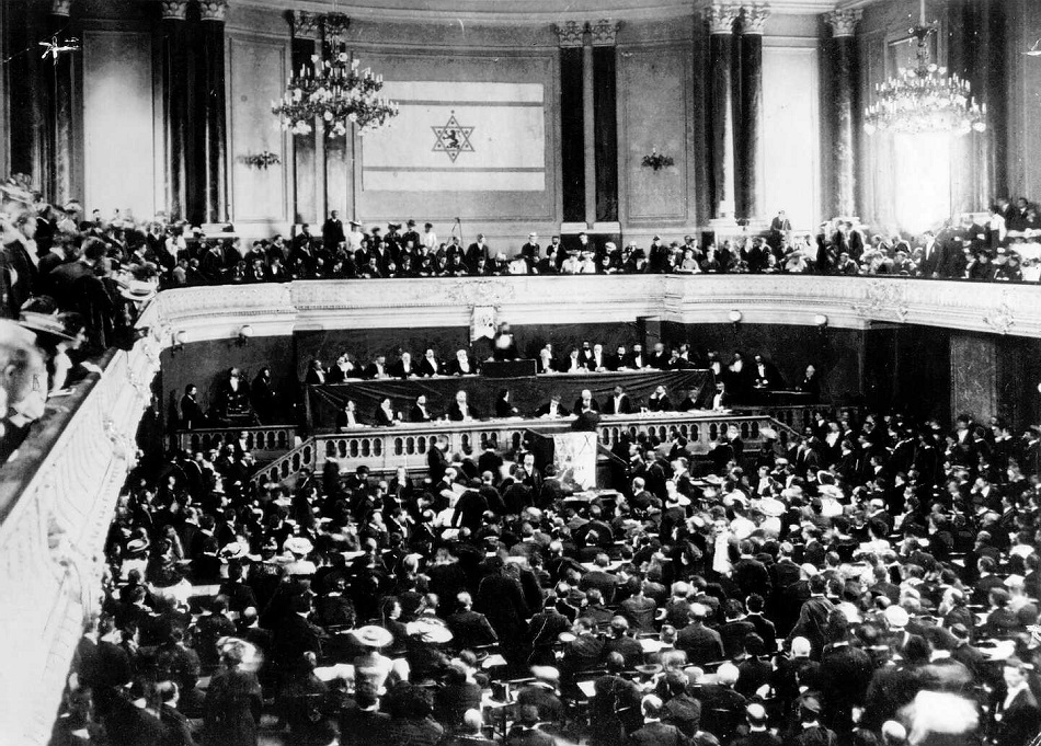 הדגל הציוני מאחורי בימת הנשיאות באולם הקונגרס הציוני השלישי בבאזל, 1899. (PHG\1052686)