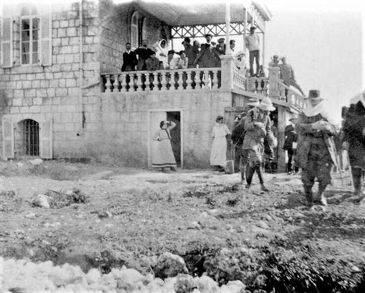 תיירים בחזית חוות הפועלים ביער חולדה (כיום "בית הרצל"), 1913. (PHG\1014428)