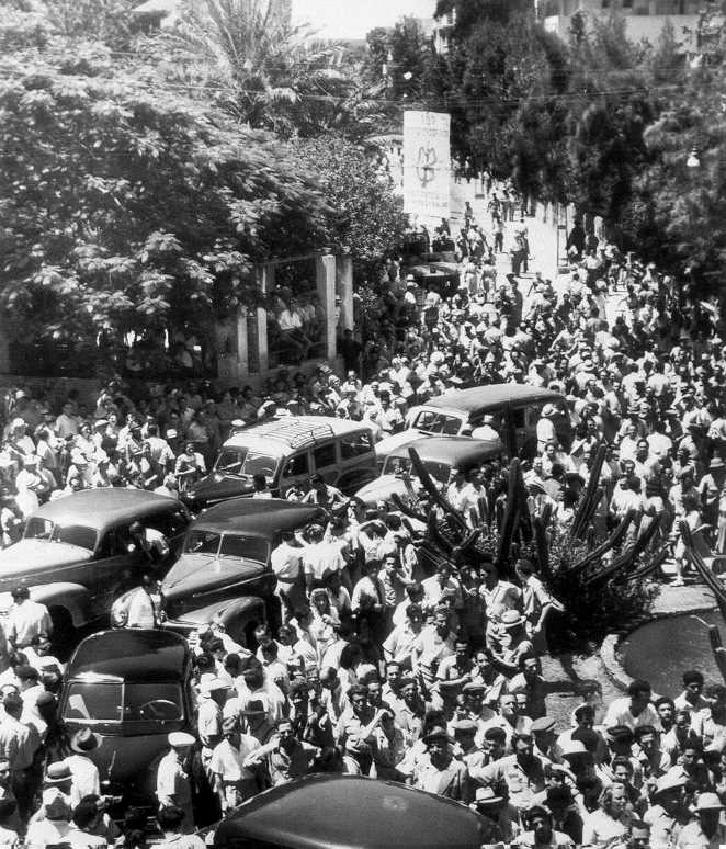 מפגינים נאספים סביב שיירת המכוניות של חברי הוועדה בתל אביב, 25.6.1947. (PHG\1085545)