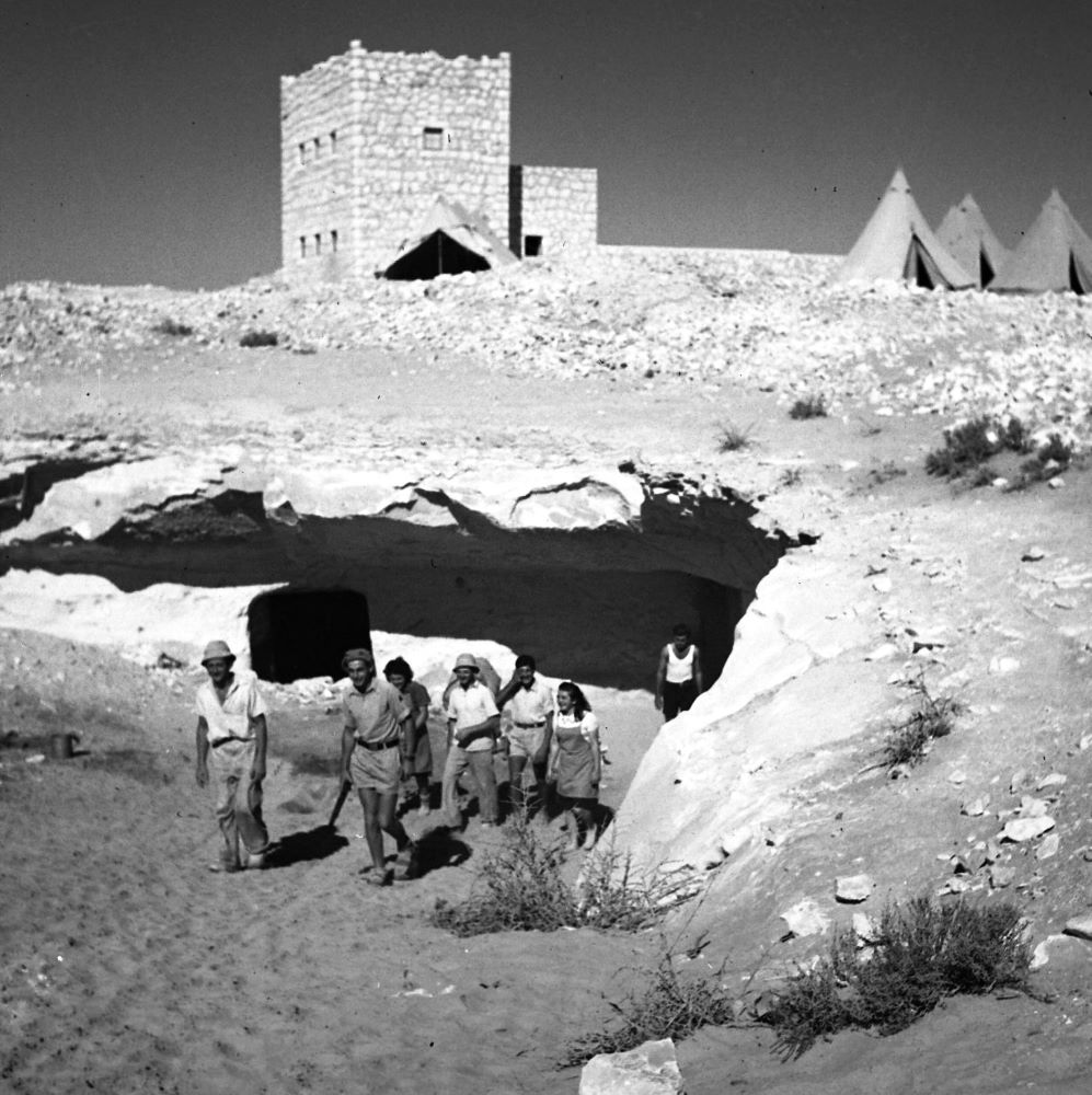 אנשי מִצפה רביבים בפתח המערה על רקע "הטירה" ואוהלי המגורים הראשונים, 1944 (NKH\484608)