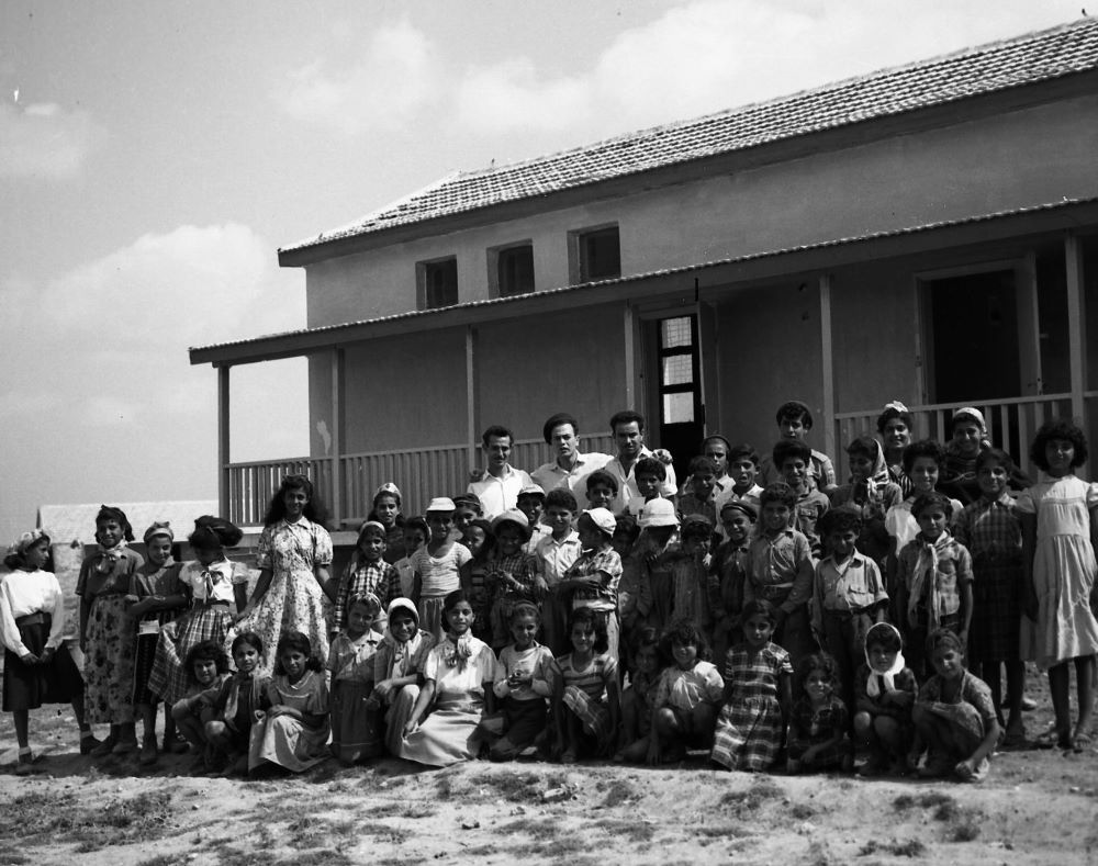 תלמידי מושב יכיני על רקע בית הספר המקומי, 1957 (NKH\426890)